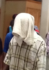 St. Jean, with his head covered, being led away from court after being sentenced in 2012