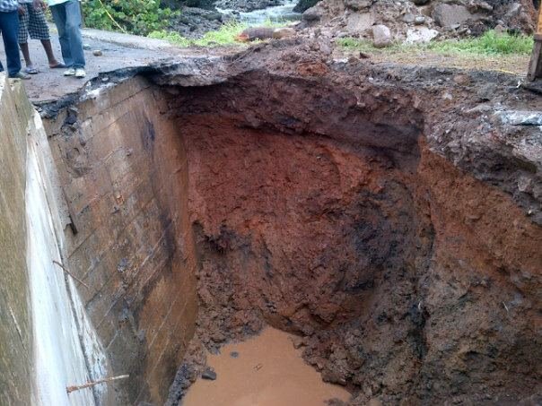 Curious onlookers examine the huge hole in the road