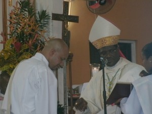 Letang (left) kneels before Bishop Malzaire during the rite of ordination