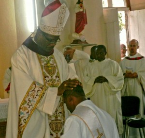 Bishop Malzaire prays over John during the rite of ordination 