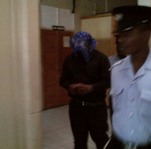 Degallerie (head covered) being led away after his conviction
