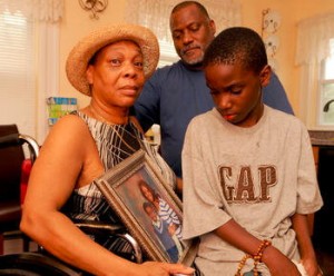 Joan White holds a photo of her daughter, Joanne, while her grandson, and her husband, Joe, look on. Photo by Boston Herald