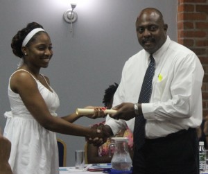 A graduate receives her diploma from Tourism Minister Ian Douglas