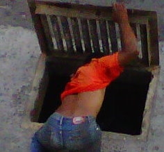 A vagrant searches for something in a drain in Roseau