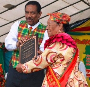 Evantie Hariette receives a plaque from President Charles Savarin. Photo courtesy of Dr. Lennox Honychurch