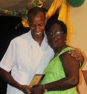 Vina Royer gets a hug from St Joseph MP Kelver Darroux after being awarded on Thursday