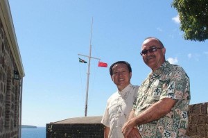 Ambassador Wang Zonglai and Dr. Lennox Honychurch with the Dominica and Chinese flags flying at Fort Shirley
