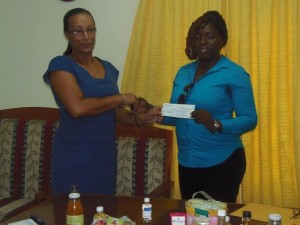 Teacher at PSS Roselyn Matthew receives a check from a DOMLEC official 