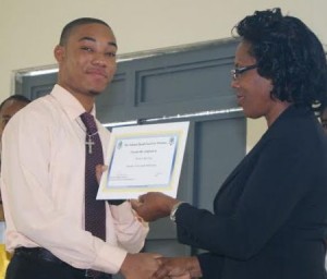 Kahn Roache receives his certification as a member of the youth media team from Youth Minister Justina Charles
