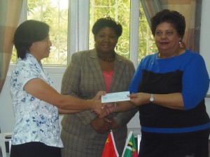 Wong Zhaoseng presents the check to Kathleen Pinard-Byrne while Helen Royer looks on