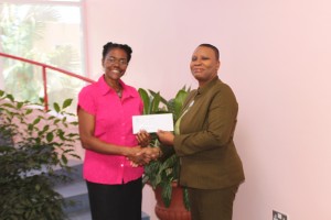 SFSS Director Pearle Christian receives $1500.00 cheque from AID Bank's, Josephine Dechausay Titre.