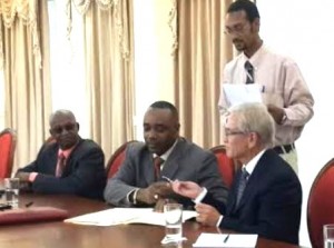 Blackmoore signs with Hobson while acting PM Ambrose George and PS in public work Kendell Johnson (standing) look on
