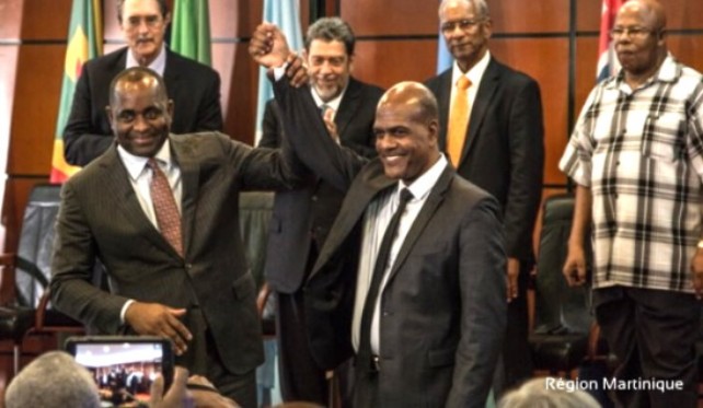 Chairman of the OECS, PM Skerrit raises the hand of Martinique’s President Serge Letchimy after the signing 