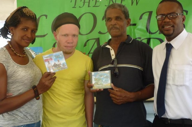 Look-Us Band lead singer Jerd Dorsette (second from left) with songwriter Ronald Charles (right) pose with two residents of Petite Savanne 