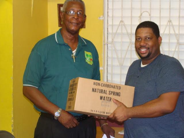 Ambrose Sylvester (left) presents water to chairman of the council, Ericson Robinson