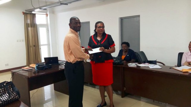Priscilla Darroux, Principal of the Delices Primary School receives check from Dr. Jeffrey Blaize 