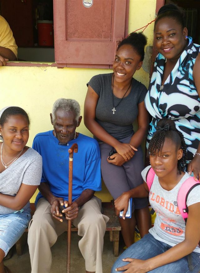 Students visit with an elderly man 