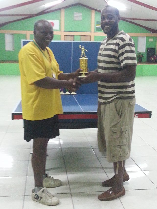 Abraham Browne, DTTA Open Singles Champion, receives his trophy from Yehudi John, Tournament Director