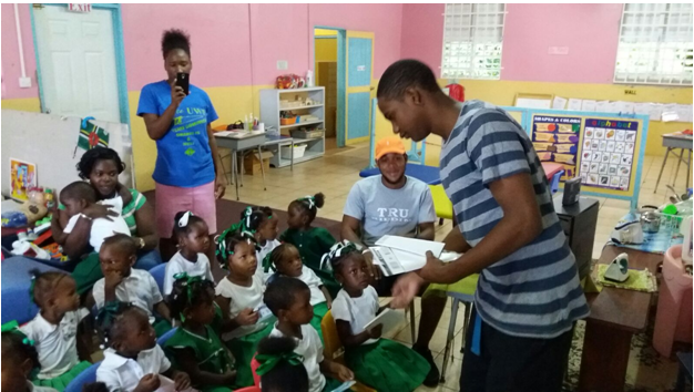 A member of Tru Riddim band distributing stationery to Portsmouth Social Centre pre-schoolers 